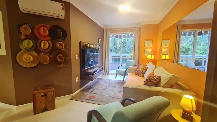 Desde el hall de entrada, vista del living, sofa cama y TV, al fondo salida al balcon y vista del morro